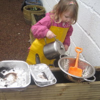 child pouring water from a kettle into a bowl