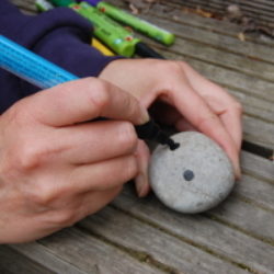 drawing eyes onto a pebble with black acrylic pen