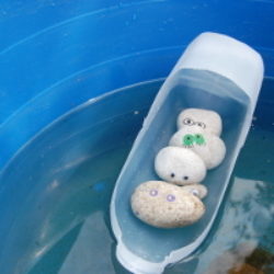 pebble creatures in milk carton boat
