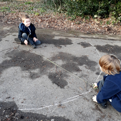 Two boys making a circle using string and stick and chalk. compass