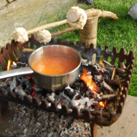 campfire bread on stick next to pan of soup