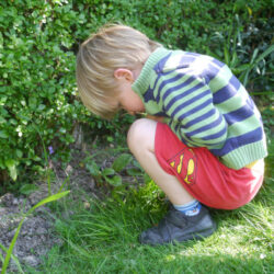 Boy squatting and looking at the ground