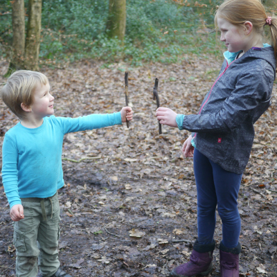 Two children comparing length of sticks
