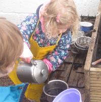 child pouring water into a teapot