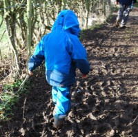 child in waterproofs stomping through mud