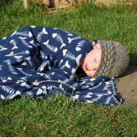 small child lying on the grass under a blanket sleeping