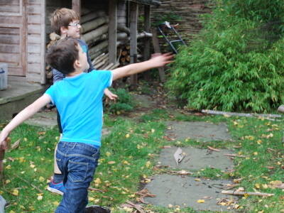 Two children slinging mud balls at a tree in the garden.
